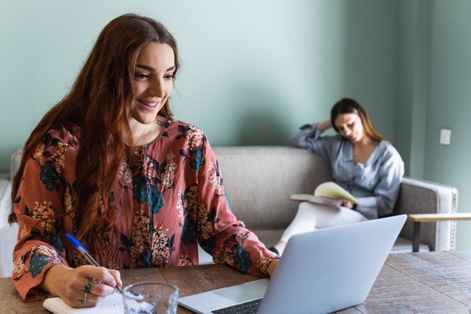 Focused woman taking notes and working on laptop