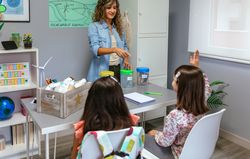 Teacher asking to girl with raising hand in ecology classroom