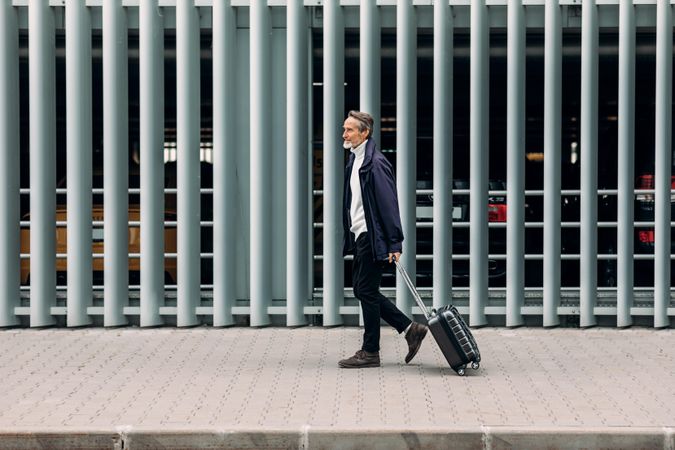 Man walking with suitcase outside airport garage