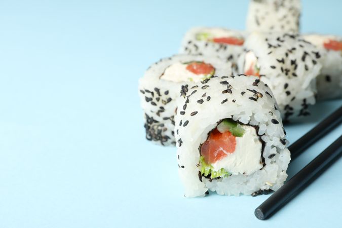 Chopsticks and sushi rolls on blue background. Japanese food