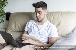 Man relaxing on sofa using laptop 426kdK
