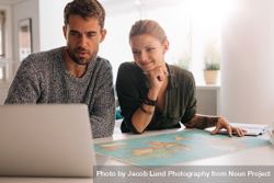 Two people planning trip with world map and laptop 5XrKqQ
