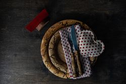 Valentine's day table setting with red dotted napkin and heart decoration on rustic plate