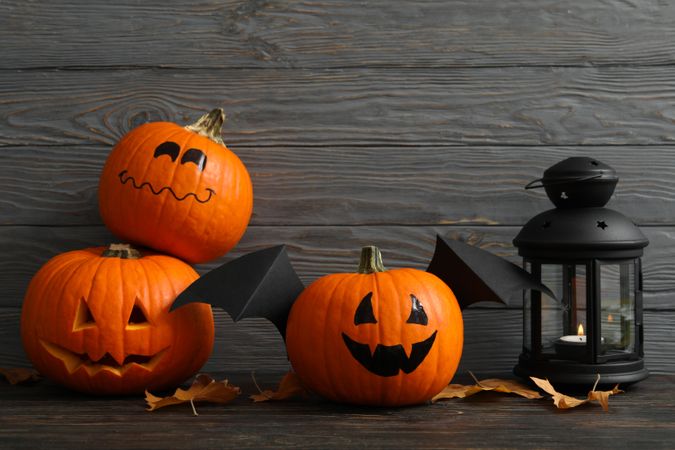 Lantern and pumpkins with wings on wooden background