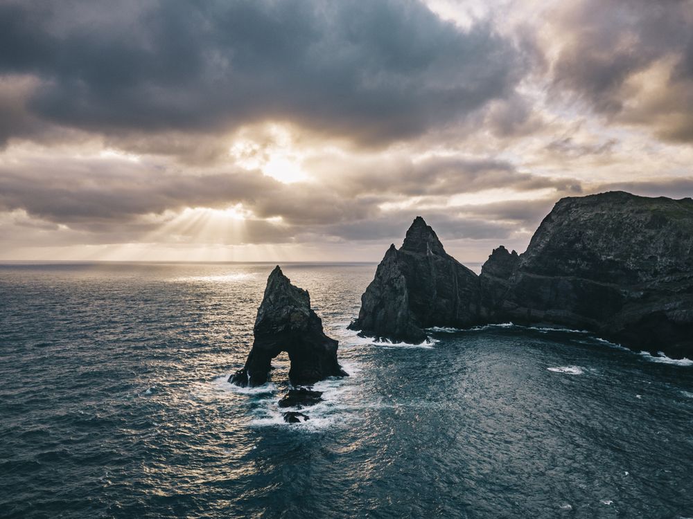 Sun peaking through the clouds along a rugged shoreline
