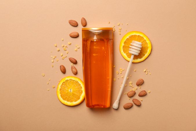 Shampoo bottle and natural ingredients on craft background. Blank space on bottle