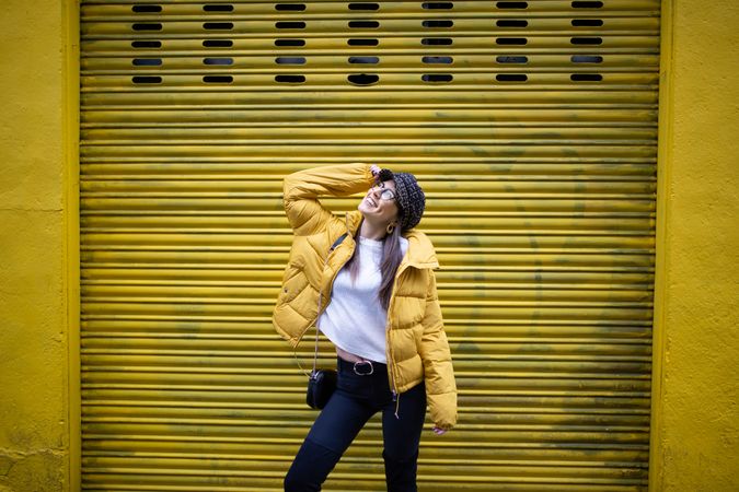 Trendy female standing near yellow wall on street