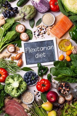 Top view of a healthy food mix fresh vegetables, fruit and fish with chalkboard in center, vertical