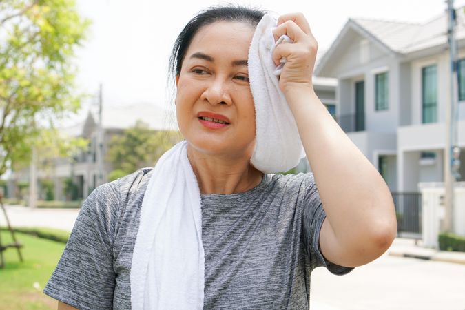 Woman using towel to wipe the sweat after workout