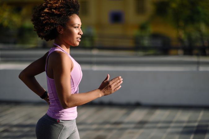 Woman with afro hairstyle running outside in sporty vest