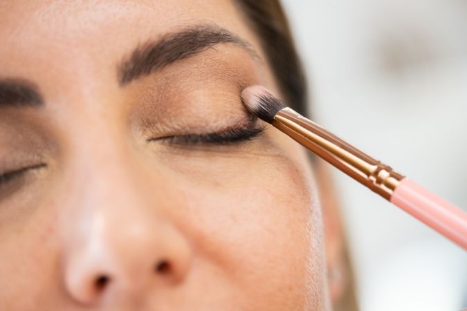 Woman having flattering eye shadow applied in salon