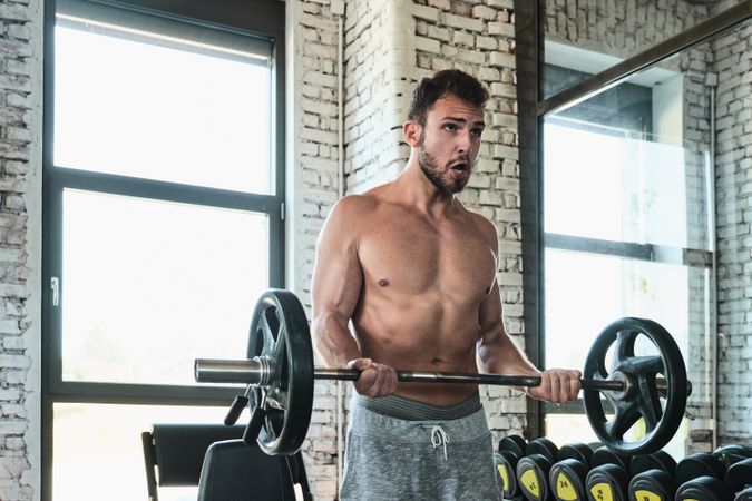 Bearded man exercising with barbell in gym