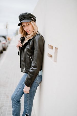 Stylish woman confidently leaning on white wall