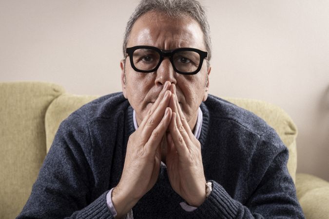Mature man praying or thinking deeply at home.