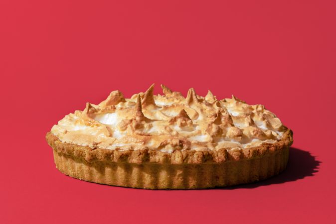 Lemon meringue pie, freshly baked, isolated on a pink background