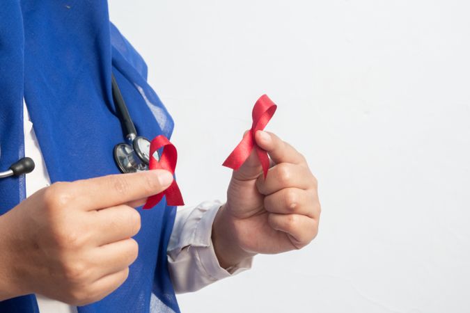 Happy Muslim Female Asian doctor or nurse holding Red ribbons, HIV awareness concept, world AIDS day, world cancer day with copy space