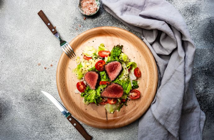 Top view of steak salad with fresh lettuce on grey table