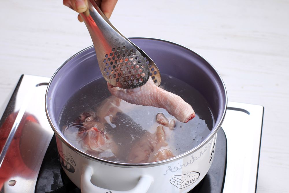 Indonesian Home Cooking, Female Hand Add Chicken Thigh Drumstick to the Pan using Tongs, Making Indonesian or Thai Style Curry, Traditional Asian Gourmet Called Opor Ayam