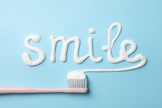 Word Smile made of toothpaste on blue background, top view