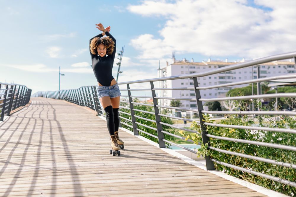 Smiling woman with afro hairstyle rollerblading on sunny day