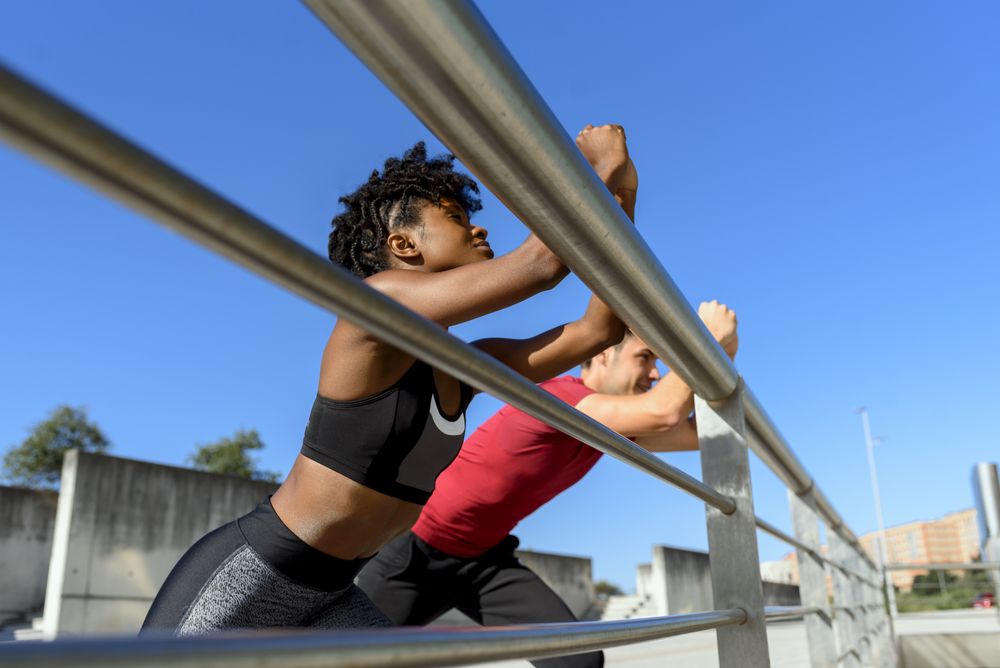 Happy young sportive couple doing stretching exercises together
