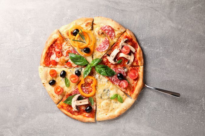 Delicious pizza with different pieces on grey background, space for text