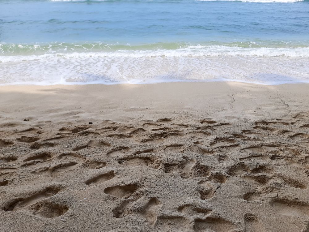 Footprints on sandy beach near ocean waves in Angso Duo Island, Pariaman, Indonesia