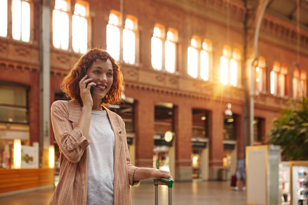 Red haired young woman using smartphone at station