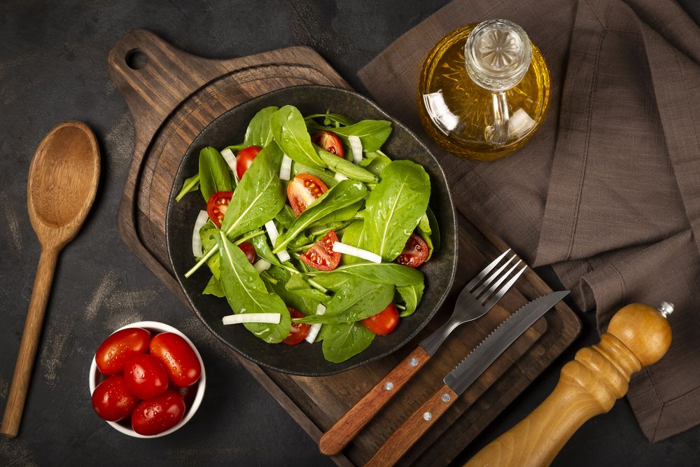Arugula salad with tomatoes on dark background.