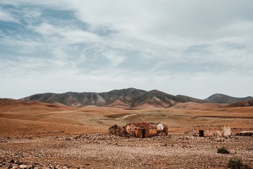 Dilapidated old buildings in mountain desert under cloudy sky