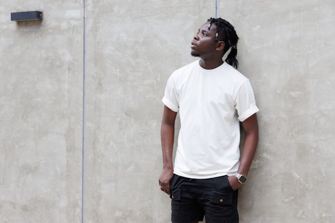Black man leaning against gray wall