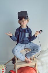 Adorable boy on stool stepladder with VR goggles on head
