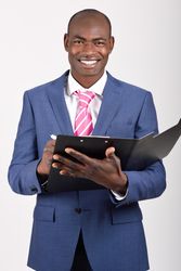 Smiling male in business attire standing and taking notes in folder