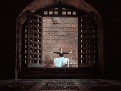 Flexible ballerina performing plie near stone wall in ancient ca