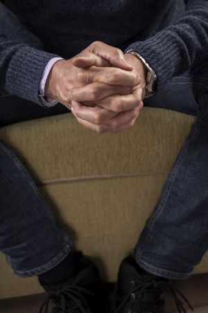 Anonymous man with clasped hands waiting anxiously.
