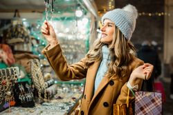 Young woman choosing jewelry at a Christmas market stall at night.