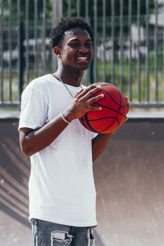Black sportsmen with ball smiling and looking away
