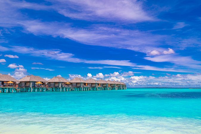 A row of overwater bungalows over clear tropical water
