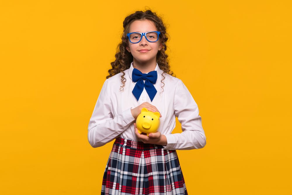 Girl with blue glasses holding yellow piggy bank