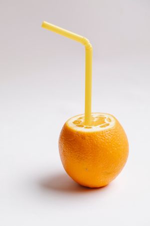 Orange fruit with straw on light surface