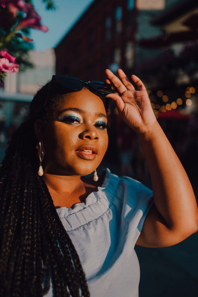 Joyful trendy Black woman standing beside blossomed tree