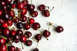 Top view of scattered sweet cherries on grey kitchen counter