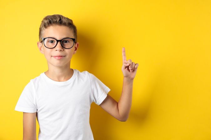 Boy in glasses against yellow background, space for text