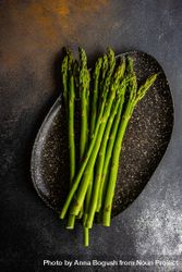 Loose raw asparagus on dark plate 49mBxL