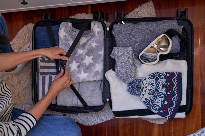 Anonymous traveler with opened packed baggage on floor