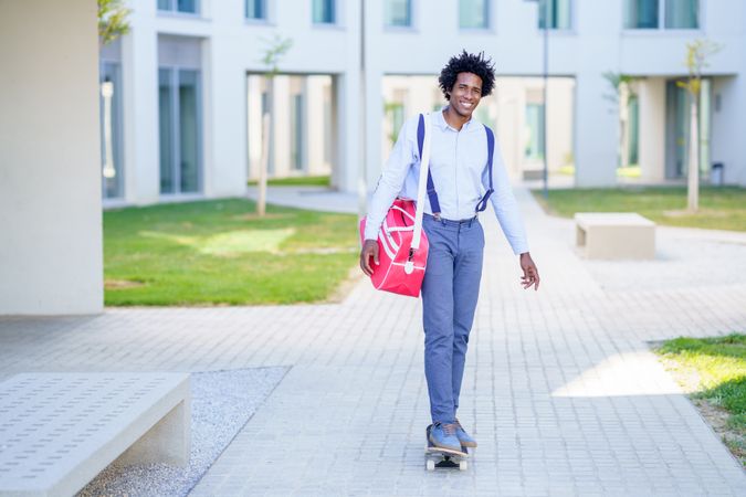 Smiling man with sports bag roller skating out of office