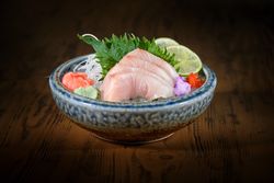 Bowl with delicious sashimi on wooden table