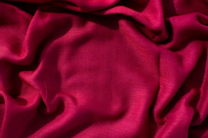 Red fabric wavy crumpled background texture with copy space.