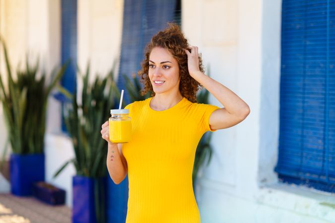 Woman in yellow dress sipping similar colored smoothie