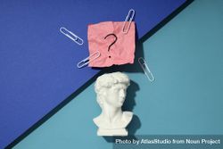 Marble bust of David with crumpled pink post it note with question mark and paper clips on blue 41xmZ5